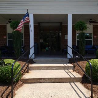 Entrance to a building with an American flag and porch plants.