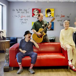 Three people enjoying music in a colorful, art-filled room.