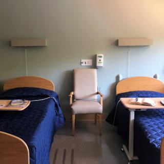 A hospital room featuring two beds and a chair, ready for patient care.