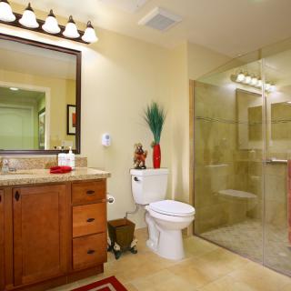 A modern bathroom featuring a glass shower, wooden vanity, and decorative accents.