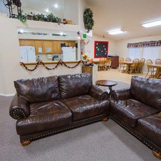 A cozy living space with leather couches and festive decor, featuring an open kitchen and dining area in the background.