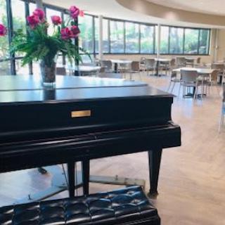 An elegant restaurant interior featuring a grand piano adorned with fresh flowers.