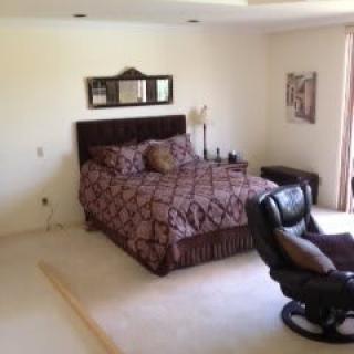 A cozy bedroom with a bed and recliner chair.