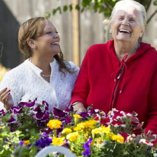 Two women enjoying time together in a colorful garden.