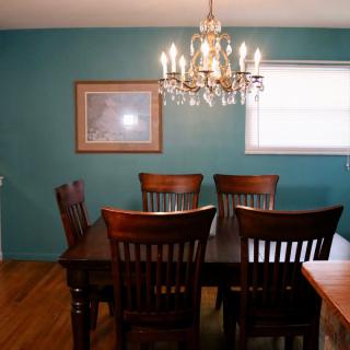 A dining room with a wooden table, chairs, and a chandelier.