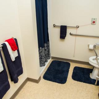 An accessible bathroom with towels, a shower, and safety bars.