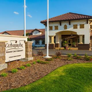 Entrance of a building with signage and landscaped grounds on a sunny day.