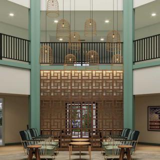 A modern lobby with decorative lighting, featuring a two-story design and green accents.