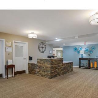 A modern reception area featuring a stone-accented desk with a large clock on the wall and colorful decorative art.