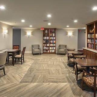 A cozy library interior with tables, chairs, and bookshelves.