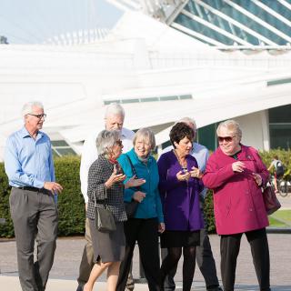A group of people walking outside near a modern architectural structure.