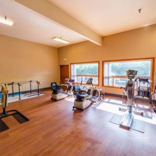 A spacious gym with various exercise equipment and large windows.