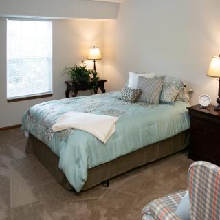 A cozy bedroom with a neatly made bed, soft lamps, and warm decor.