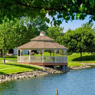 A serene gazebo by the water, surrounded by lush greenery.