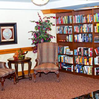 A cozy reading corner with a bookshelf, chairs, and a small table.