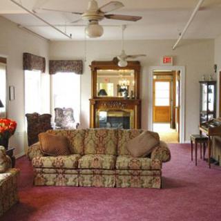 A cozy living room with a patterned sofa, carpeting, and a large mirror above the fireplace.