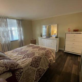 A cozy bedroom with a bed, dresser, mirror, and window with curtains.