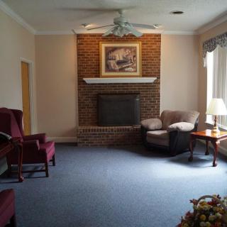 A cozy living room with a brick fireplace, armchairs, and a sofa alongside a coffee table.