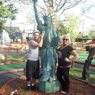 A fun day at the miniature golf course with a playful pose near a miniature Statue of Liberty.