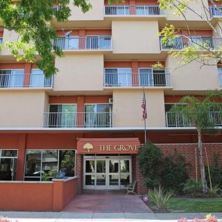 A front view of a hotel building with multiple windows and an entrance surrounded by greenery.