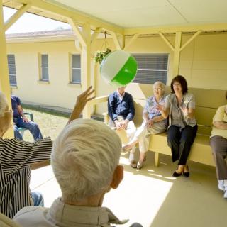 A group of elderly people engaging in a ball toss activity outdoors.