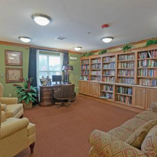 Cozy library room with bookshelves, comfortable seating, and natural light.