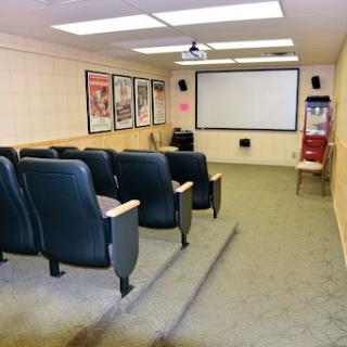 A cozy theater room equipped with seating, a projector screen, and movie posters on the walls.
