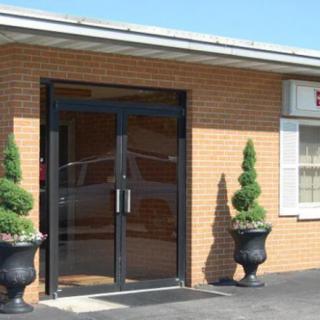 Entrance to a brick building with glass doors and decorative potted plants.