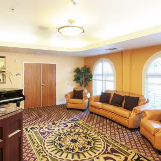 A cozy living room with leather seating, a patterned carpet, and large windows letting in natural light.