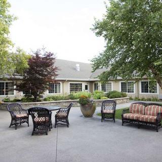 A spacious patio area with comfortable seating surrounded by trees and a house in the background.