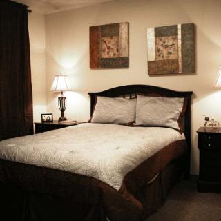 A cozy bedroom with a neatly made bed, bedside tables, and decorative artwork on the walls.