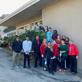 A cheerful team gathering outside a building, showcasing camaraderie and teamwork.