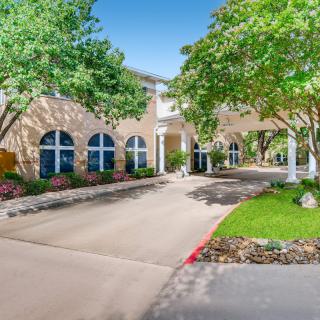 A well-maintained building with a driveway, surrounded by trees and landscaping.