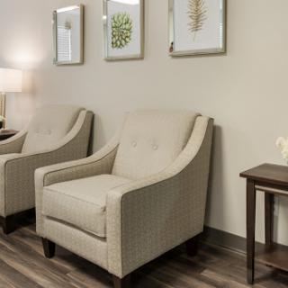 A cozy living space featuring two elegant chairs, a side table, and stylish wall art.