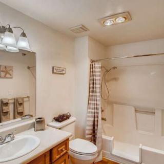 A well-lit bathroom with a sink, toilet, and shower area.