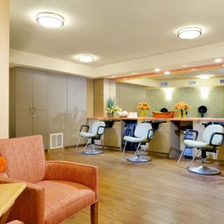 A modern hair salon interior featuring styling chairs, large mirrors, and a comfortable waiting area.