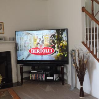 A living room with a television displaying a Bertolli advertisement.