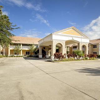 A view of a large building with an arched entrance and landscaped surroundings under a clear blue sky.