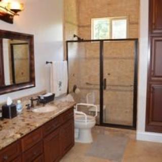 A well-appointed bathroom with a glass-enclosed shower, granite countertops, and wooden cabinetry.