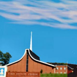 A church building with a prominent steeple against a clear blue sky.