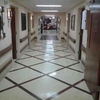A well-lit hospital corridor with patterned tile flooring.