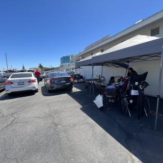 A parking lot with cars and a bicycle under a tent on a sunny day.