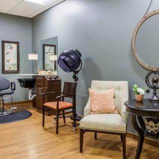 A cozy and well-decorated hair salon interior with seating and styling equipment.