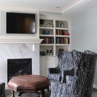A cozy living room featuring a stylish fireplace, comfortable armchairs, and built-in bookshelves.