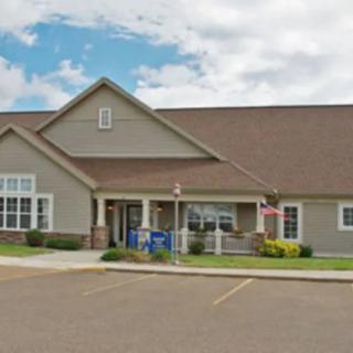 A residential-style building with a parking area in front, set against a partly cloudy sky.