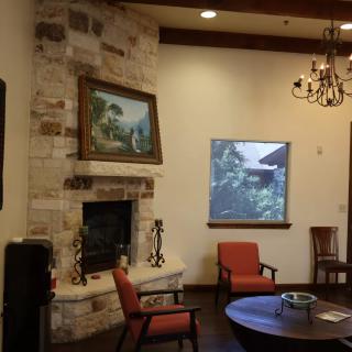 A cozy living room with a stone fireplace, chandelier, and seating area.