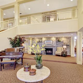 A spacious lobby with elegant decor, featuring a grand piano and a cozy fireplace.