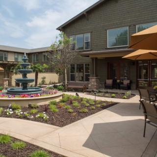 A courtyard with a fountain and outdoor seating surrounded by landscaped gardens.