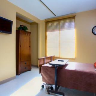 A well-lit hospital room with a bed, television, and window.