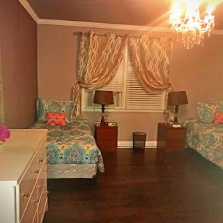 A cozy bedroom featuring two twin beds, elegant curtains, and a stylish chandelier.
